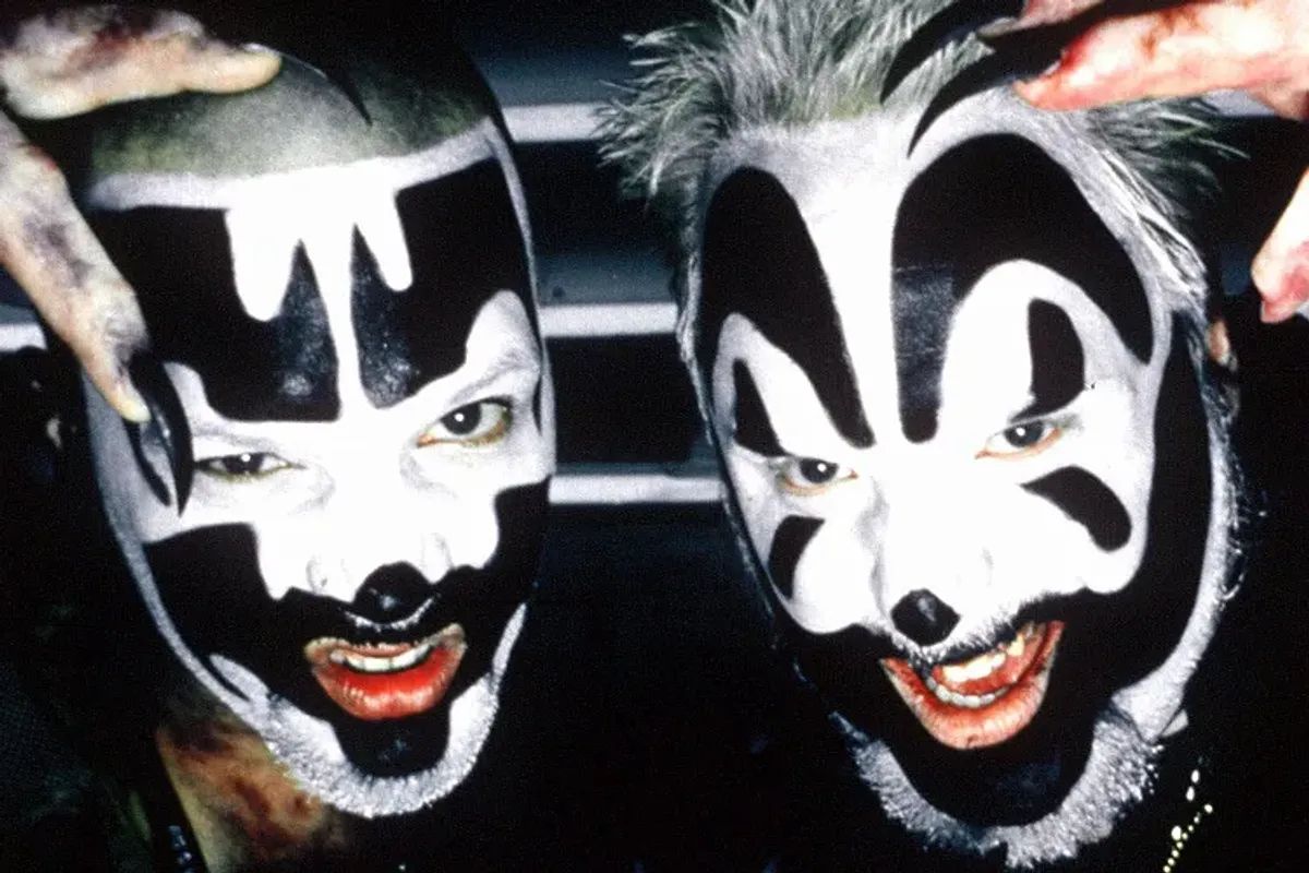 two juggalos in an extreme closeup showing just their face with striking and bold black and white makeup and claws on their fingernails.webp